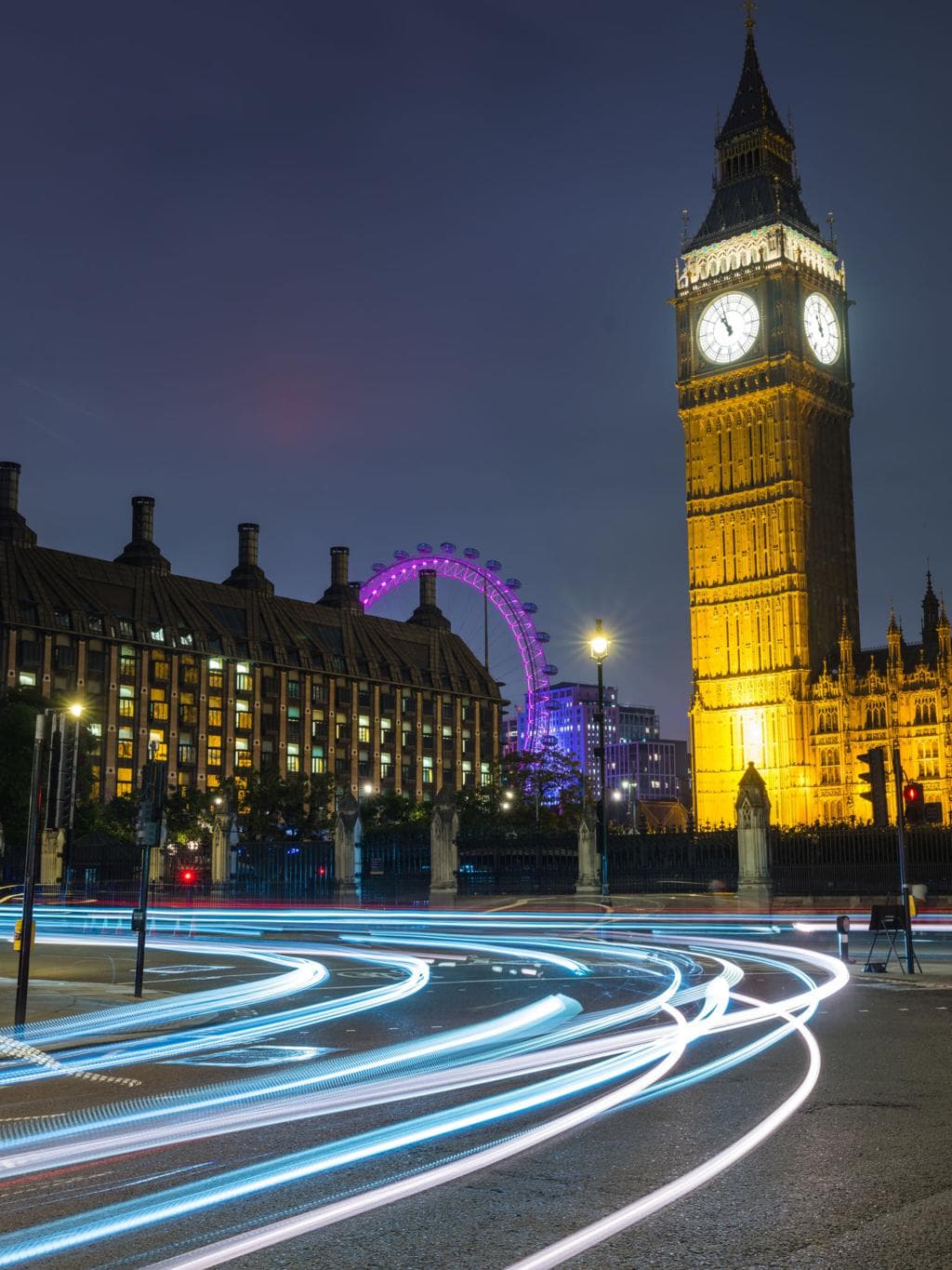 Big Ben and the London Eye at night with light trails from passing traffic